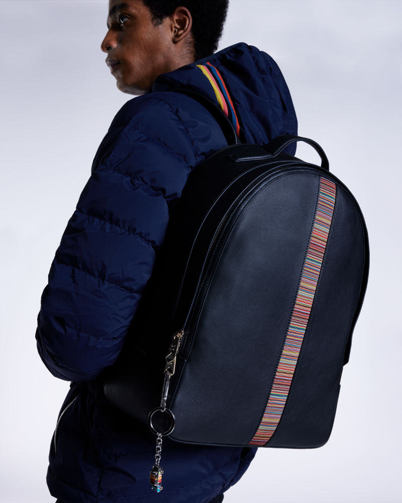 a male model wearing a black leather bag on one shoulder with colourful stripe detail down the middle and keychain hanging from the zip