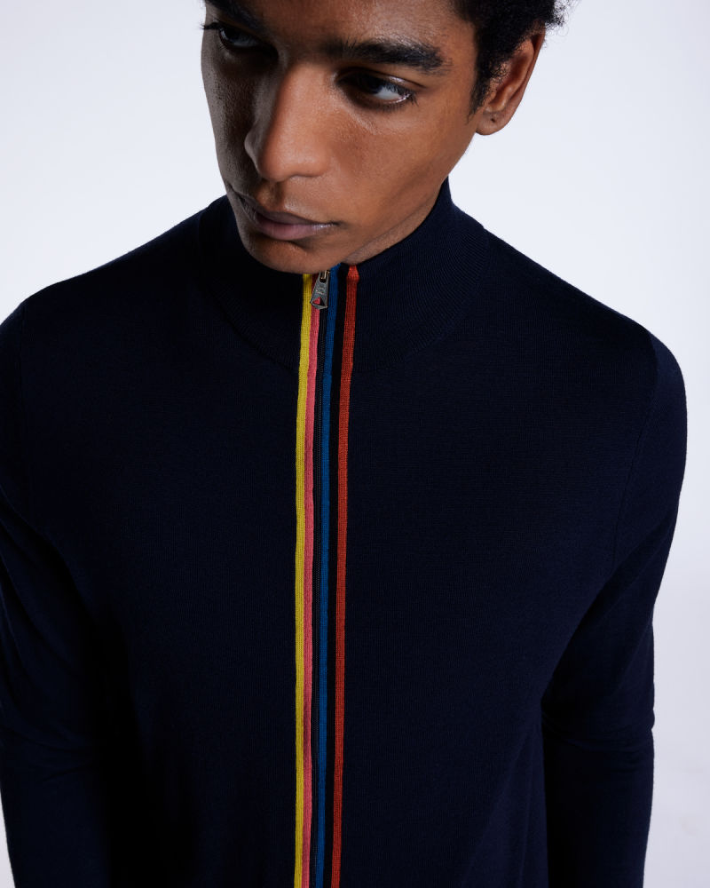 a male model wearing a navy knitted zip up jacket with colourful vertical stripes along the zip