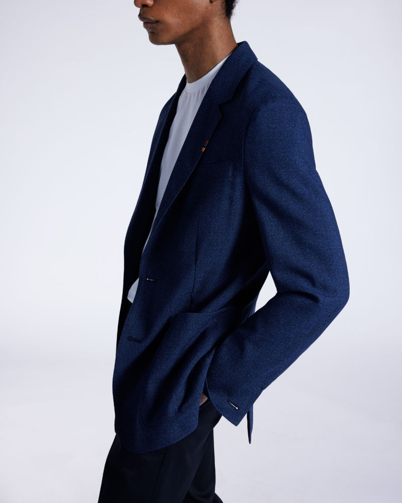a male model wearing a casual navy blazer with a white t-shirt underneath and navy trousers
